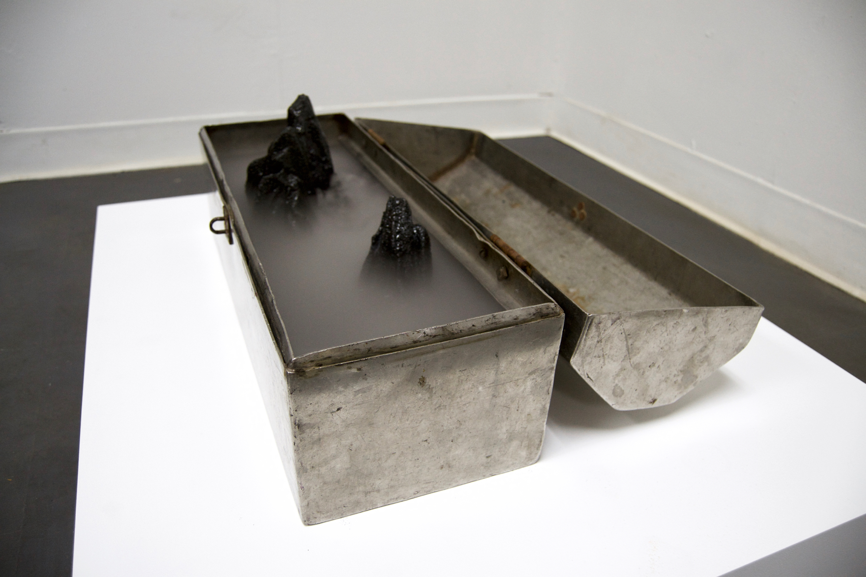 Caroline Hatfield, Depths and Distances, 2019, 5.5" x 20.5" x 15", found object (tool box), resin bonded coal slag, water, mist maker