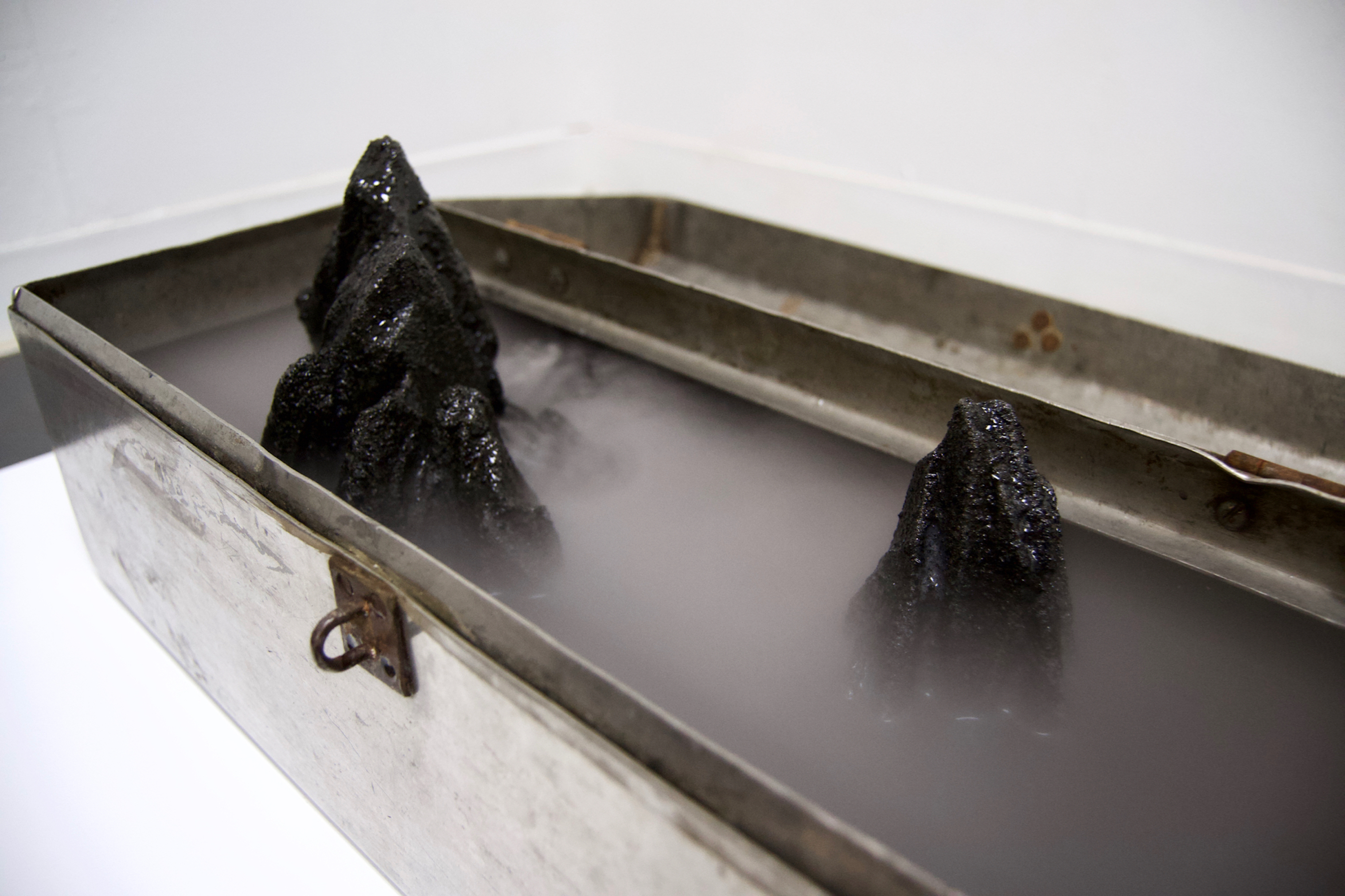 Caroline Hatfield, Depths and Distances, 2019, 5.5" x 20.5" x 15", found object (tool box), resin bonded coal slag, water, mist maker